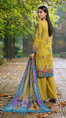 Model seated on a wooden park bench on a golden autumn avenue in a chartreuse olive luxury lawn suit with tonal vine and multicolour wildflower print, bold teal ikat cuff border, plain olive yellow palazzo trousers, and teal-to-lavender chiffon dupatta with oversized purple magnolia blooms pooling on the bench
