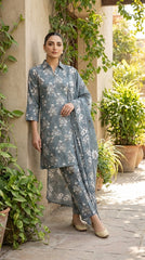 Full length front view of a model leaning against a garden wall in a steel blue 3-piece unstitched lawn suit with white blossom print and matching dupatta