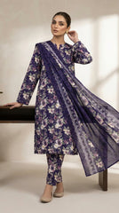 Full length front view of a model leaning against a dark wooden console in a royal indigo watercolour floral lawn suit with matching printed trouser and matching indigo chiffon dupatta with silver lace border panels flowing, warm beige background