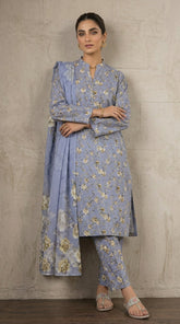 Full length front view of a model wearing a periwinkle blue Pakistani luxury lawn suit with scattered ivory rose print and a large floral bamber chiffon dupatta