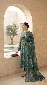 Portrait of a model wearing a pine green Pakistani lawn suit with a matching printed bamber chiffon dupatta draped over the head, gold circular earrings