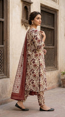 Side portrait of a model in an antique ivory botanical floral lawn suit with a geometric ikat stripe chiffon dupatta draped over one shoulder, looking away, Mughal carved wooden door background