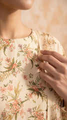 Full length front view of a model in a cream botanical print luxury lawn suit with a matching all-over printed chiffon dupatta draped over both arms, standing in a bright studio