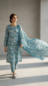 Full length front view of a model in a deep teal Pakistani luxury lawn suit with ivory cherry blossom print and a flowing bamber chiffon dupatta