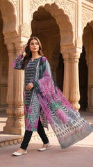 Full length front view of a model standing in a Mughal archway colonnade in a charcoal grey luxury lawn suit with ikat dot and magenta chrysanthemum print, plain charcoal shalwar, and matching printed lawn dupatta with chevron geometric border draped over one arm, warm golden light