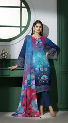 Back view of a model turning and holding out the magenta-to-teal ombré chiffon dupatta with oversized watercolour magnolia blooms in front of a green panelled wall with circular window, teal-to-magenta ombré luxury lawn suit and navy cigarette trousers visible