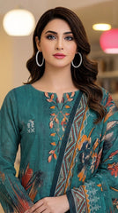 Close-up portrait of a model in a colourful pendant-light studio wearing a rich teal luxury lawn kameez with abstract ikat floral placement print in orange, rust, and navy, V-notch neckline with embroidered orange and teal leaf motifs, and matching dark teal printed lawn dupatta with geometric chevron border draped over one shoulder, silver hoop earrings