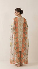Full length front view of a model in an ivory Pakistani luxury lawn suit with scattered wildflower print standing under Moroccan stone arches with a coral tulip chiffon dupatta