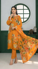 Back view of a smiling model looking over her shoulder in a green-panelled studio with circular window wearing a marigold orange luxury lawn suit with all-over oversized watercolour peony and hibiscus floral print, plain orange cigarette trousers, and matching printed lawn dupatta with coral border trailing to the floor